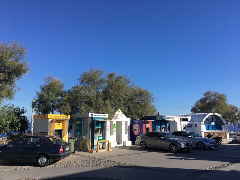 Autók parkolnak Santorinin, Oia városában a buszmegálló mellett. 