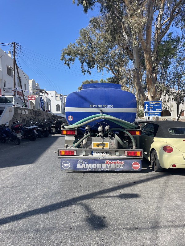 Fira egyik legforgalmasabb részén egy tartálykocsi akadályozza a forgalmat, balra motorbérlő cég 